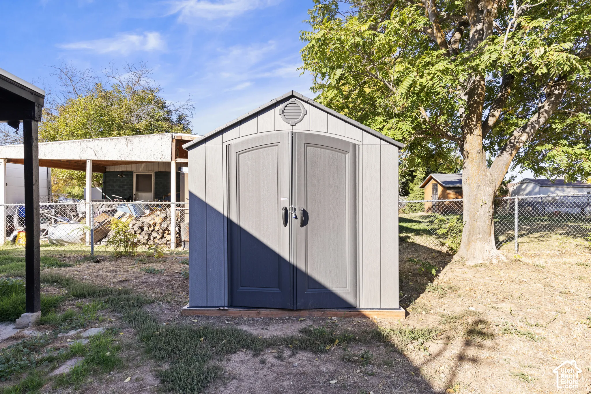 Detached resin storage shed with double doors and a gabled roof, situated on a wooden base