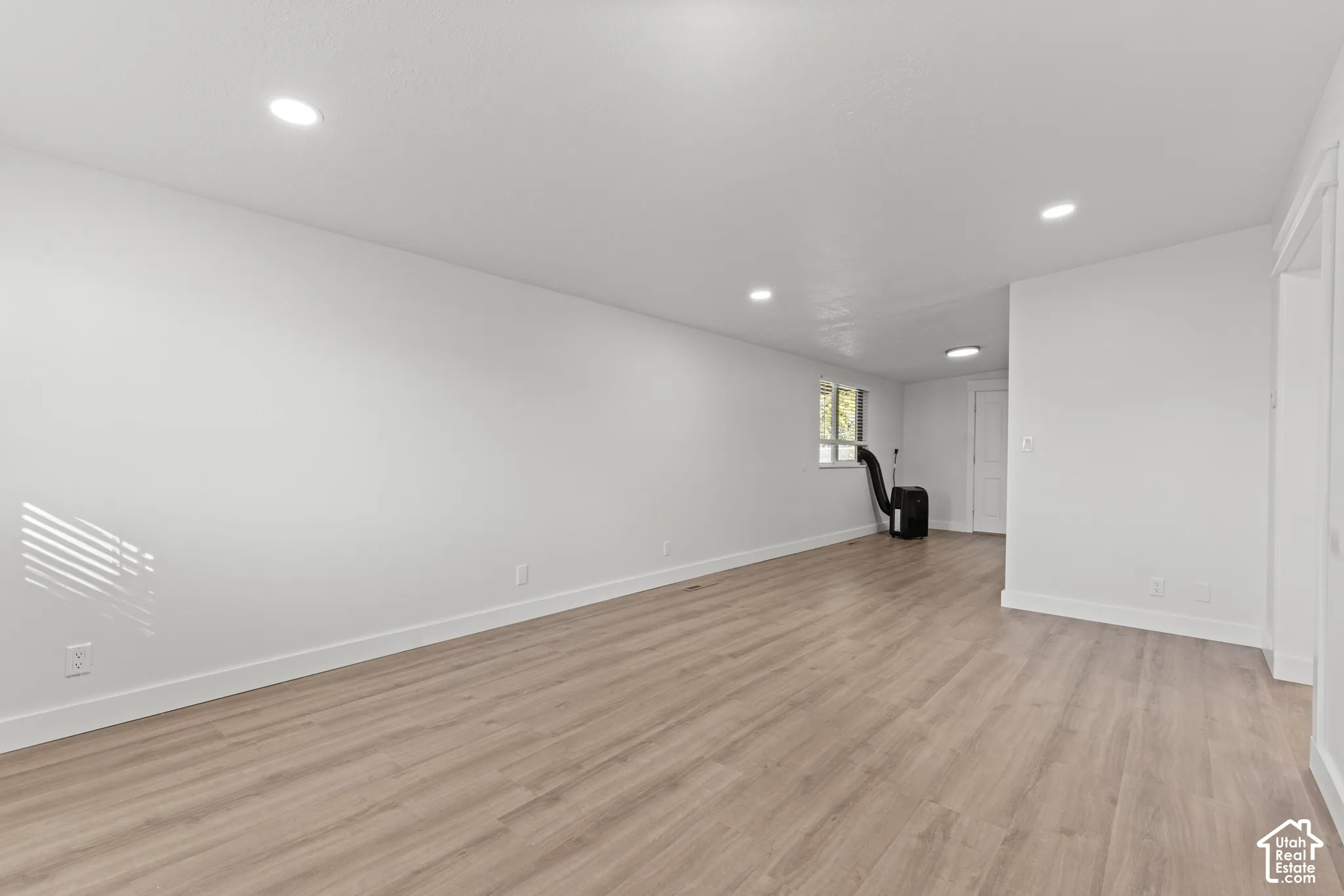Interior space featuring neutral wall paint, wood-finish flooring, and recessed ceiling lighting
