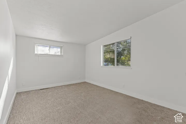Neutral-toned wall paint, carpeted flooring, and windows with horizontal blinds