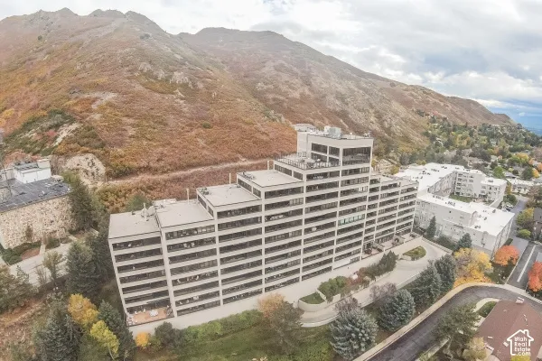 Multi-level concrete residential building featuring expansive balconies, an integrated parking structure, and a mountainous backdrop