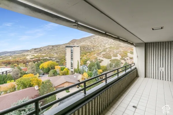 Covered balcony featuring tile flooring, metal railings, and a prominent mountain backdrop
