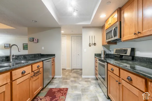 Kitchen featuring natural finish wood cabinetry, dark stone countertops, stainless steel appliances, recessed lighting, and tile flooring