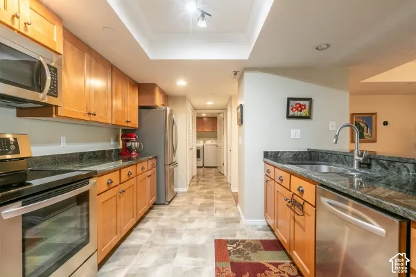 Kitchen featuring natural wood cabinetry, dark stone countertops, stainless steel appliances, and tile flooring