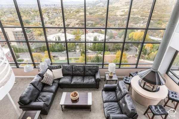 Floor-to-ceiling multi-pane windows, elevated circular fireplace with a stone-finish hearth, and curved staircase railing