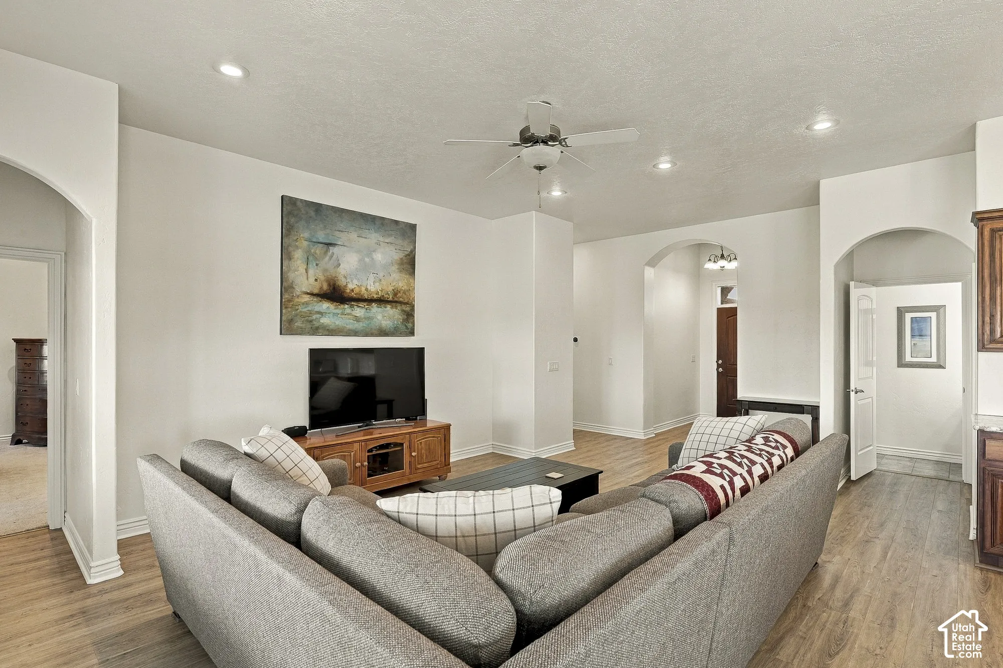 Interior space featuring wood-finish flooring, recessed lighting, a central ceiling fan, and arched architectural entryways