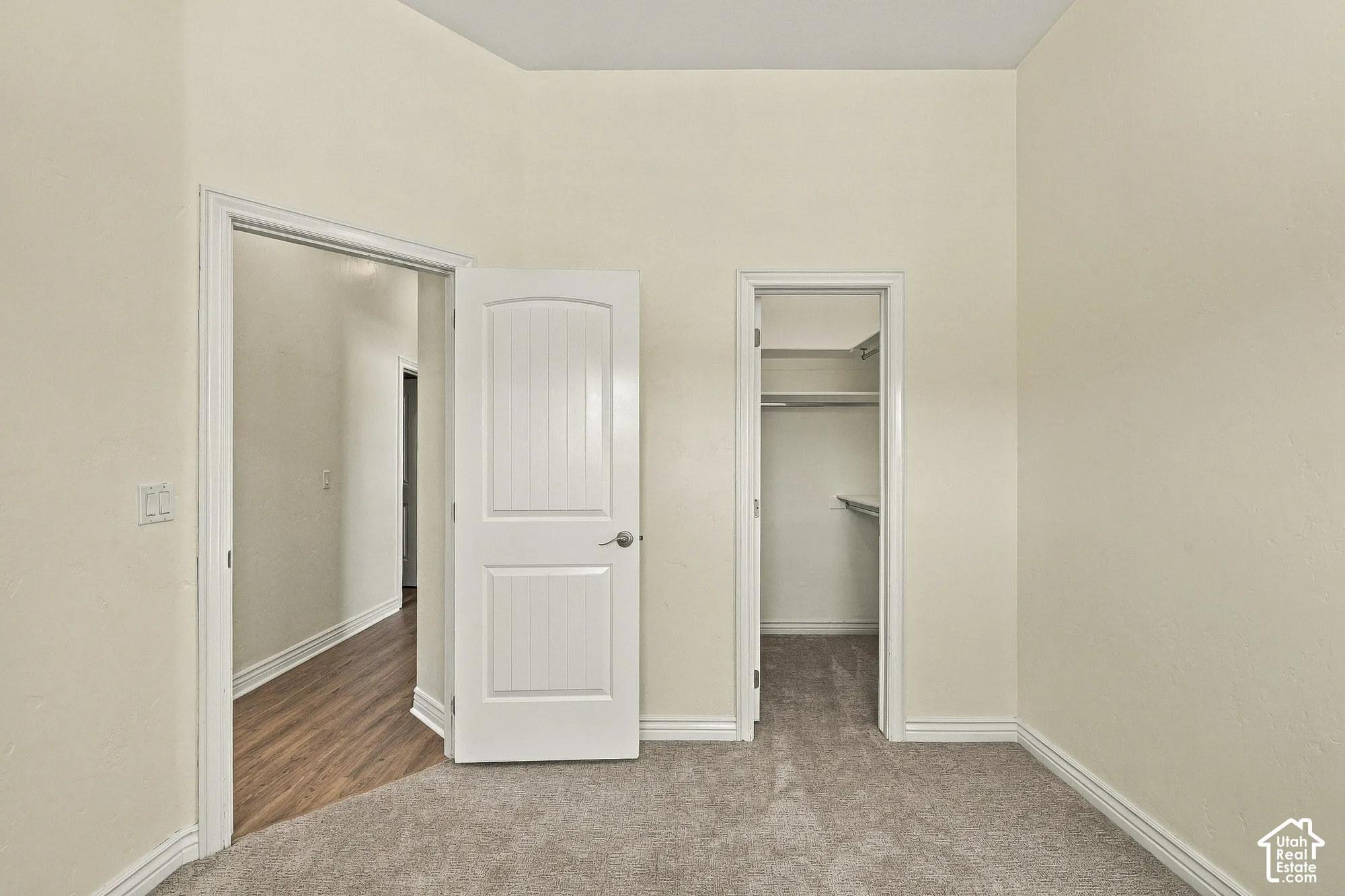 Room featuring neutral wall tones, carpet flooring, a two-panel interior door, and a built-in closet with integrated shelving