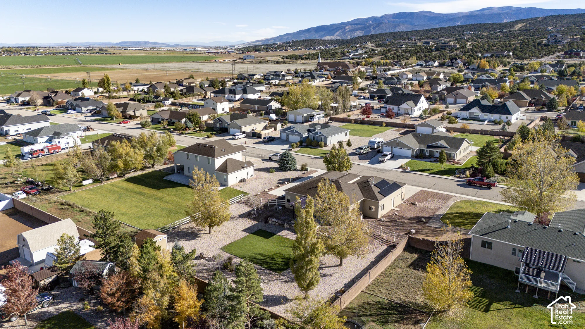 Aerial perspective featuring residential lots, landscaped yards with mature trees, and a mountain backdrop