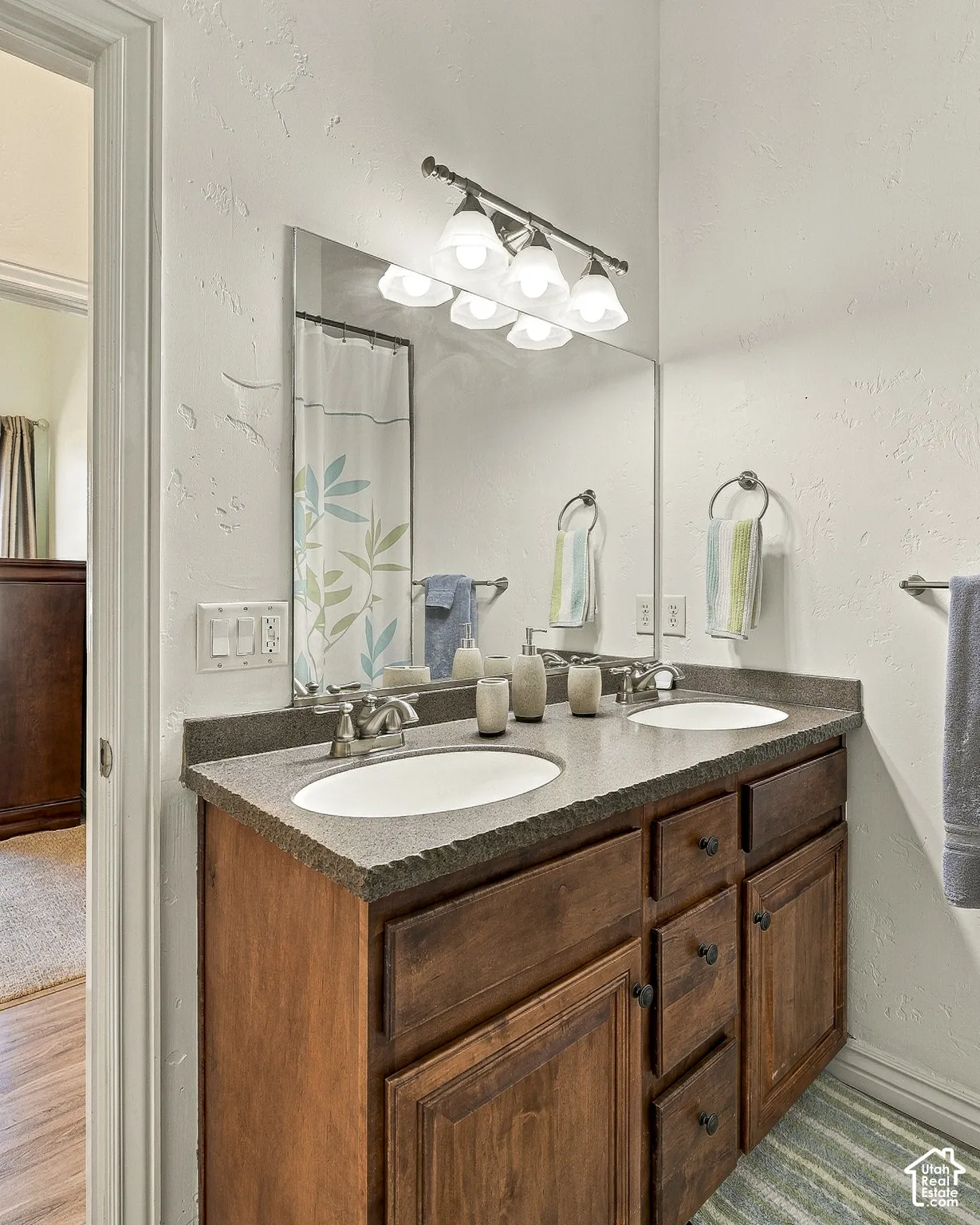Double vanity featuring a stone-composite countertop with integrated dual sinks, wooden cabinetry with drawers, and a multi-light fixture