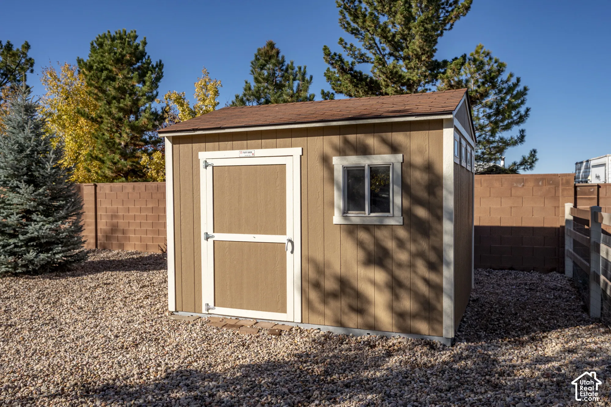 Storage structure with light brown siding, white trim, shingle roof, and a single window