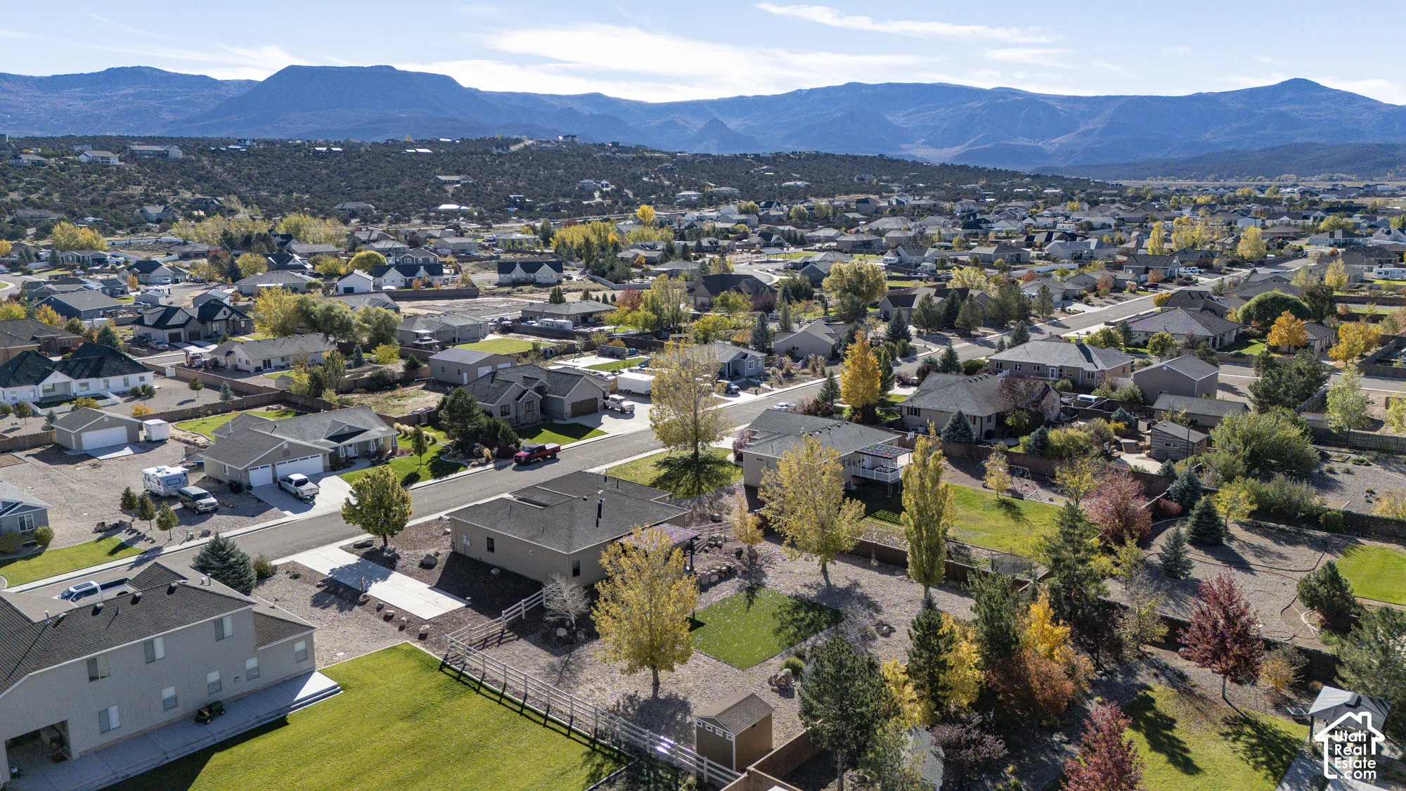 Aerial perspective featuring a landscape of residential lots, mature trees, and an expansive mountain range backdrop