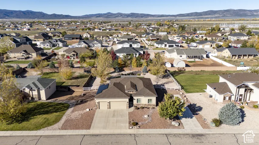 Single-story residence featuring a multi-gable roofline, solar panels, attached two-car garage, stone facade accents, and a landscape with gravel ground cover