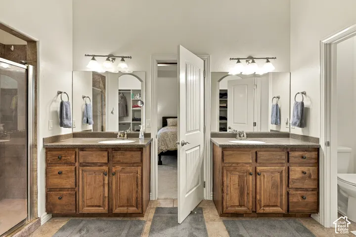 Dual wooden vanities featuring stone-surface countertops, integrated sinks, framed mirrors, and multi-light wall fixtures