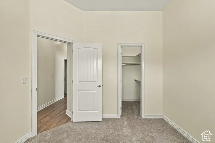 Room featuring neutral wall tones, carpet flooring, a two-panel interior door, and a built-in closet with integrated shelving
