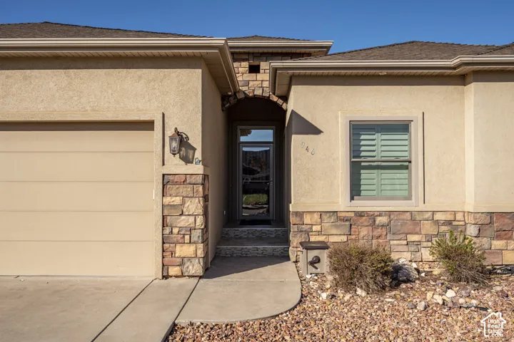 Stucco exterior featuring natural stone accents, arched entryway, and attached garage