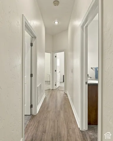 Hallway featuring wood-finish flooring, recessed lighting, and white paneled doors