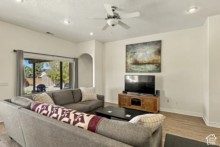 Living area featuring wood-finish flooring, recessed lighting, a ceiling fan, and an arched entryway