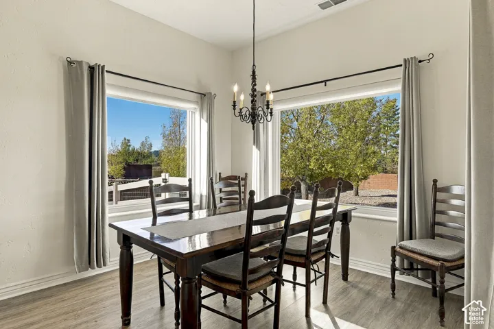 Dining area featuring wood-finish flooring, high ceilings, large windows, and a decorative wrought-iron chandelier