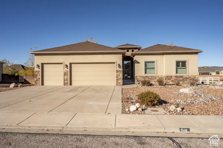 Single-story exterior featuring a stucco facade, stone veneer accents, multi-car garage, concrete driveway, and recessed entry
