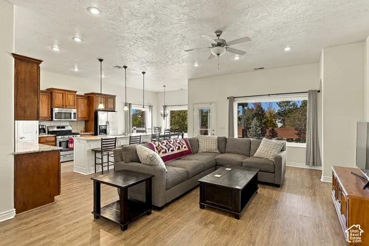 Open floor plan featuring wood-finish flooring, recessed lighting, a center island with pendant lighting, and large picture windows