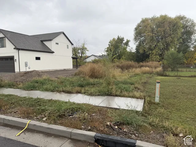 Corner lot featuring a concrete sidewalk, mature trees, and vertical siding exterior