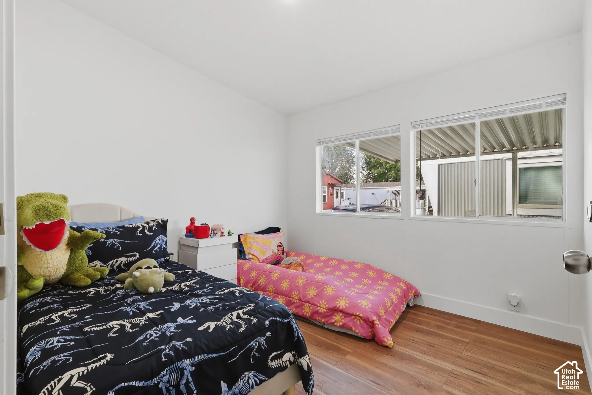 Room featuring crisp white walls, wood-finish flooring, and dual horizontal windows
