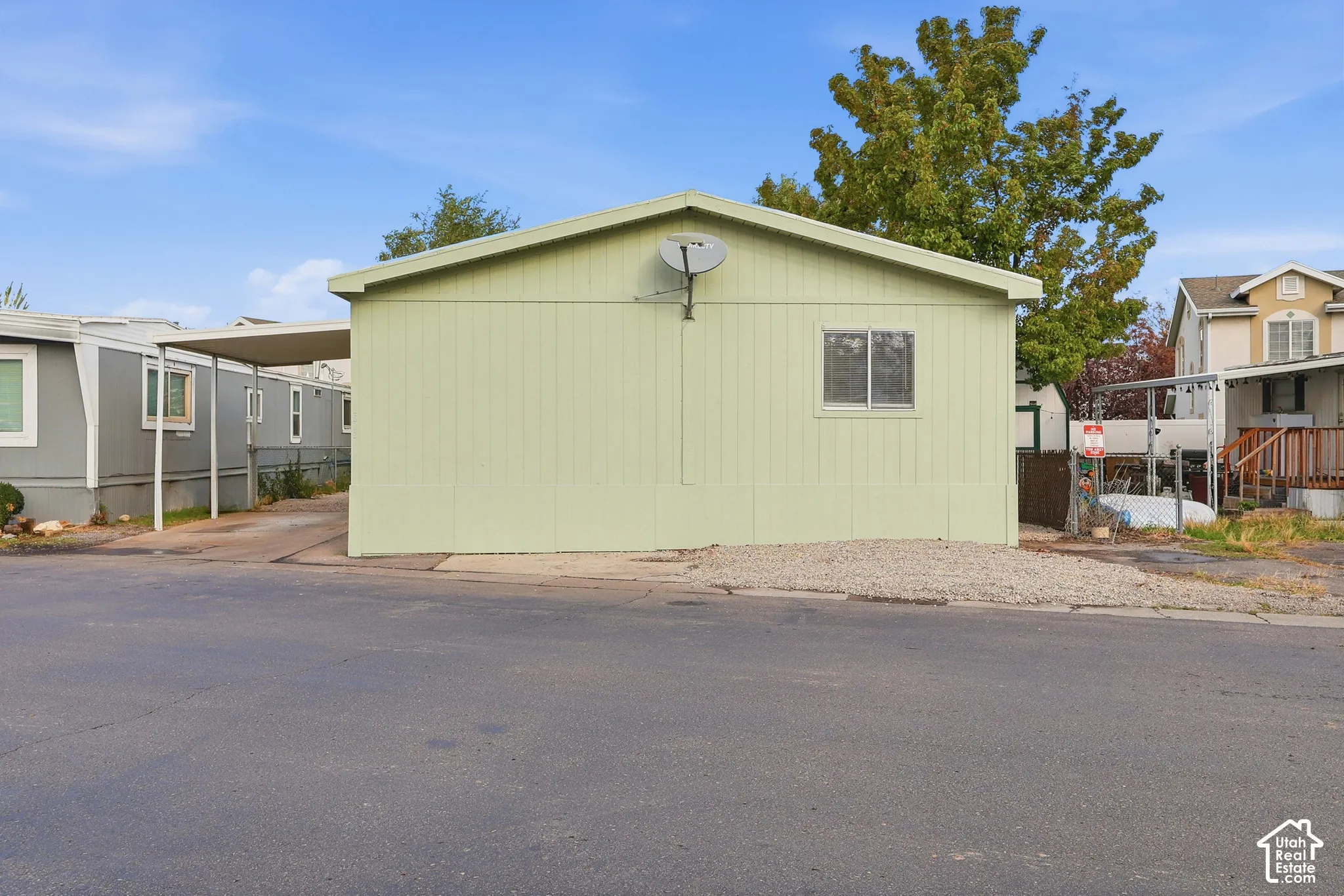 Single-level exterior featuring vertical siding, a low-pitch roof, an attached carport, and a low-maintenance gravel front landscaping area