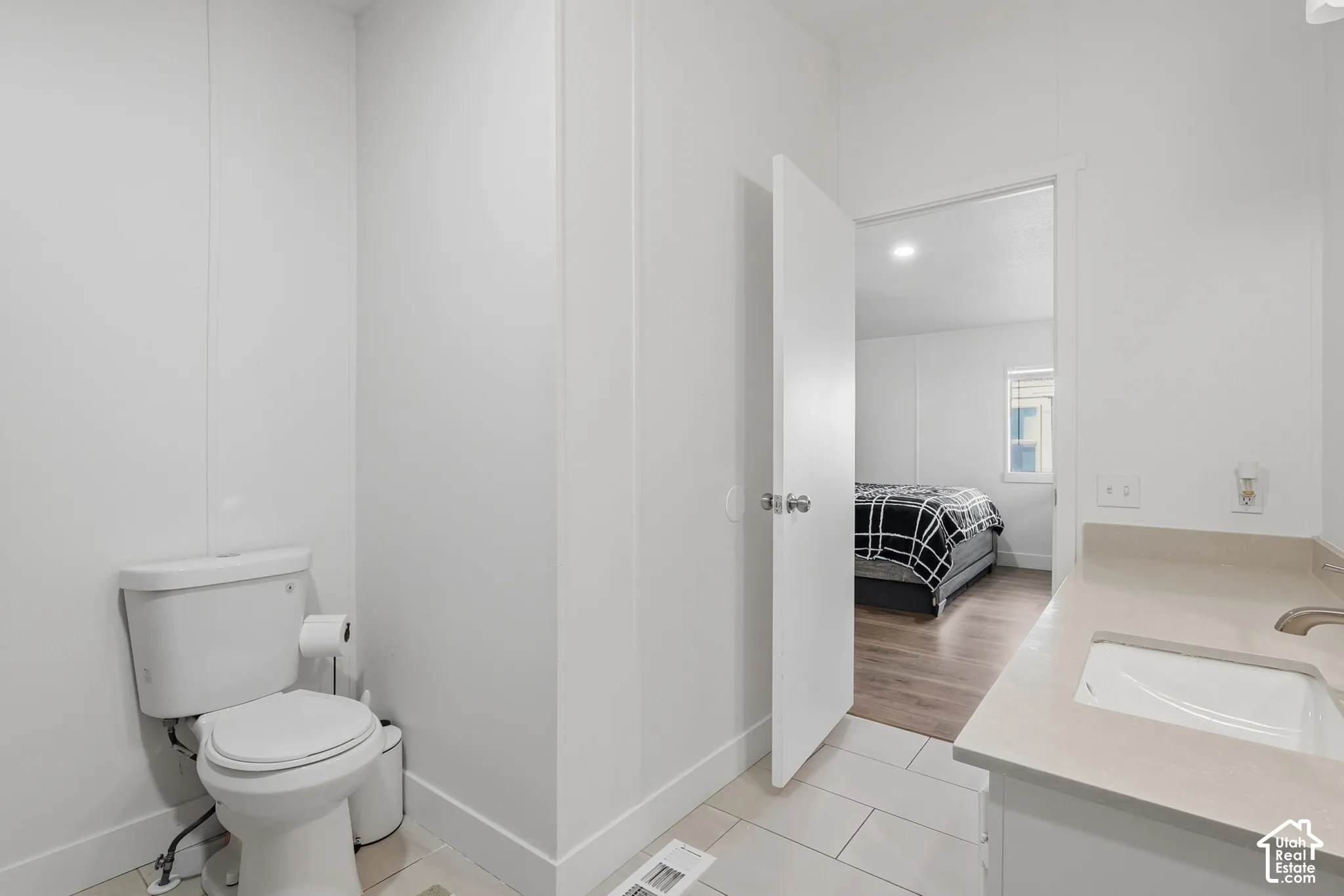Bathroom featuring a neutral-toned vanity with an integrated basin, a light-colored solid surface countertop, and large-format tile flooring