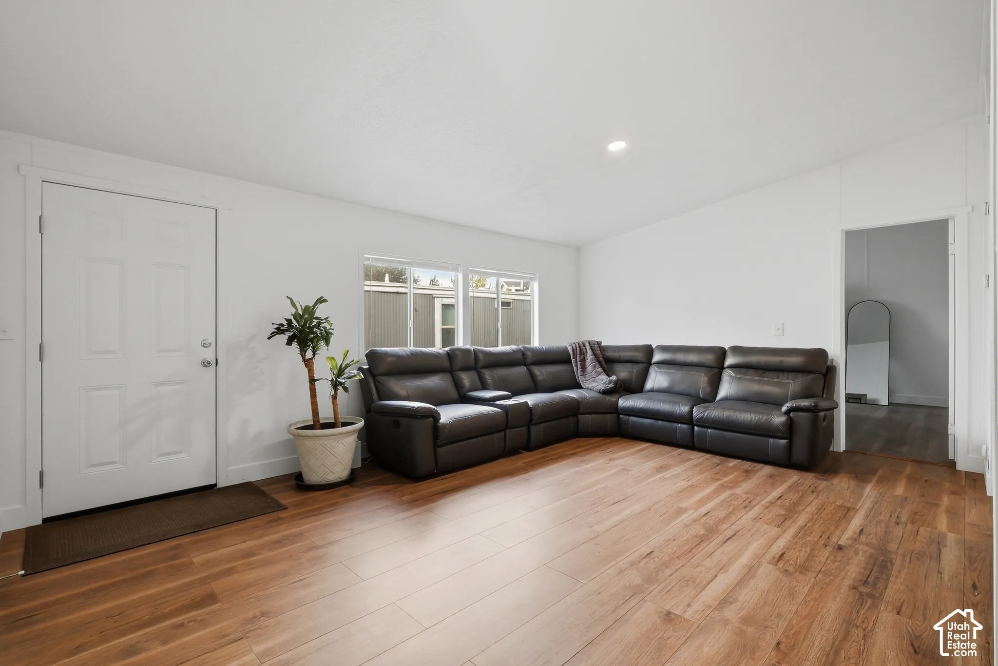 Neutral-toned living space featuring wood-finish flooring, dual-pane windows, and recessed lighting