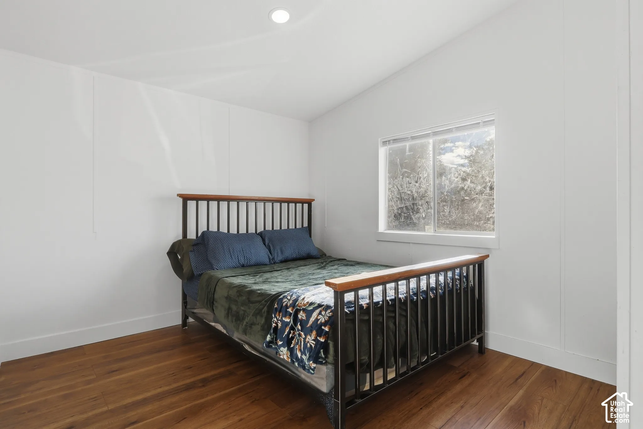Vaulted ceiling with recessed lighting and wood-finish flooring