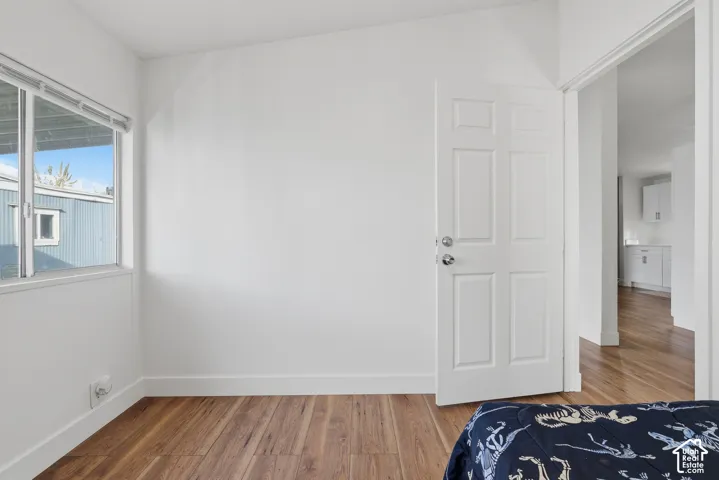 Room featuring wood-finish flooring, white walls, and a multi-panel interior door