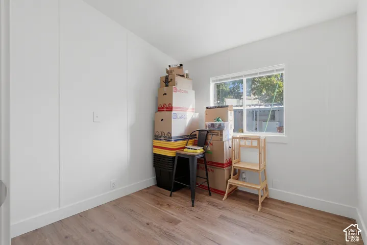 Interior room featuring neutral wall finishes, wood-finish flooring, and a single-pane sliding window with white trim