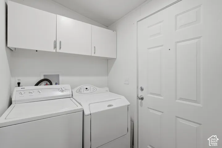 Laundry area featuring white built-in upper cabinetry, white paneled door, and recessed plumbing hookups