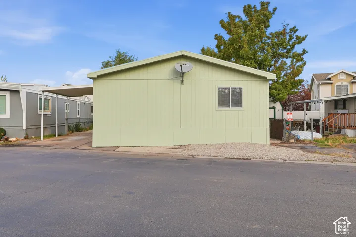 Single-level exterior featuring vertical siding, a low-pitch roof, an attached carport, and a low-maintenance gravel front landscaping area