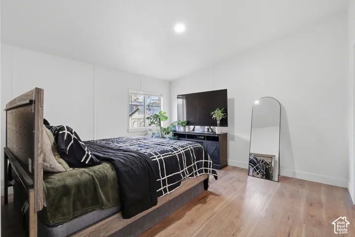 Neutral-toned interior space featuring wood-finish flooring, white walls, and a recessed ceiling light