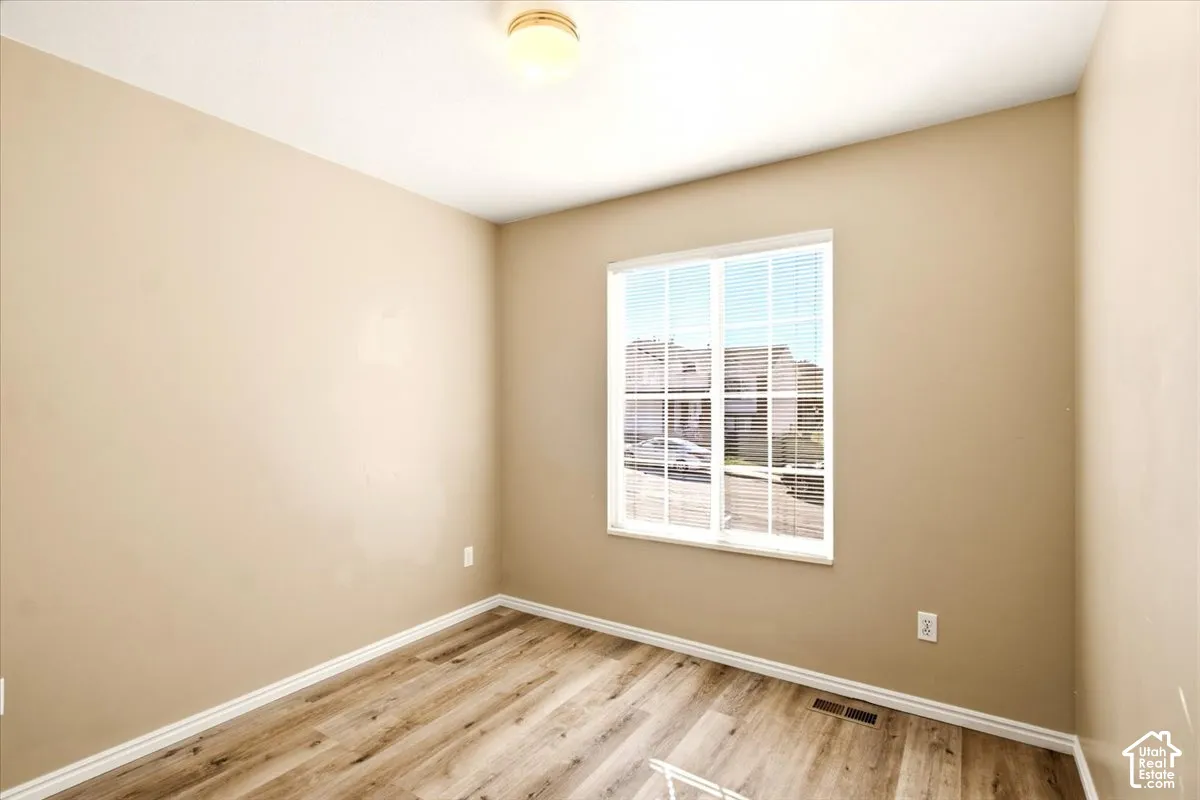 Neutral wall tones, wood-finish flooring, and a single-window configuration featuring colonial-style muntins and a ceiling-mounted light fixture