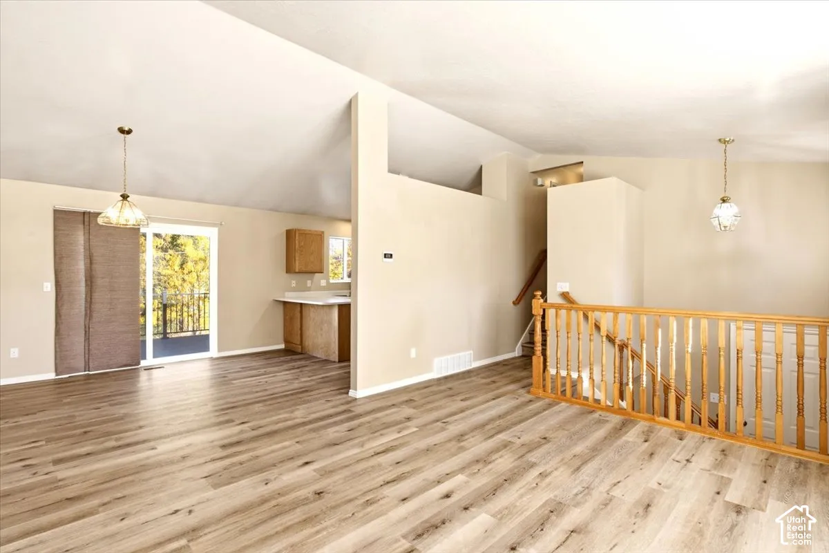 Vaulted ceilings, wood-finish flooring, sliding glass doors, and a wood baluster railing
