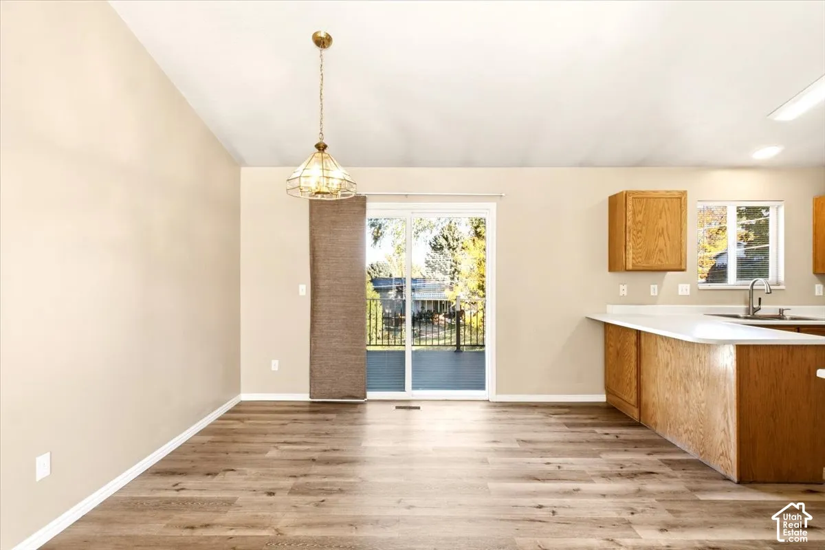 Wood-finish flooring, sliding glass door, pendant lighting, peninsula with countertop, and wood-finish cabinetry
