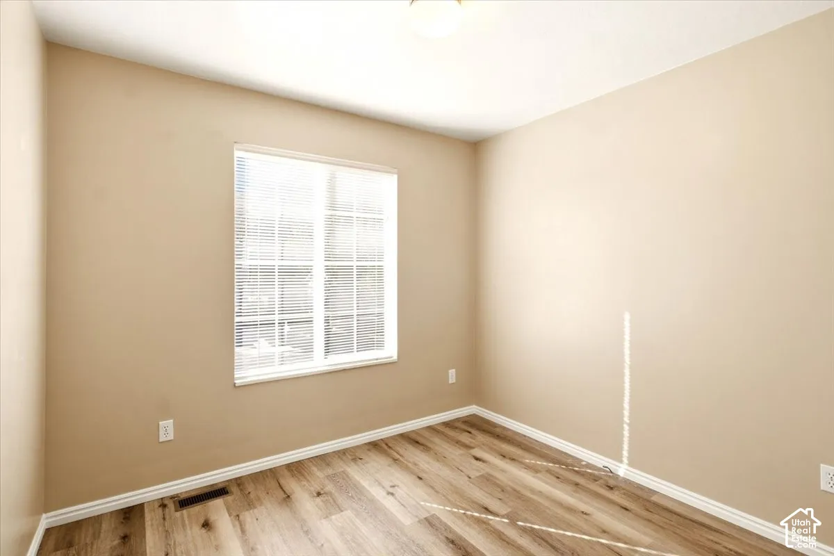 Neutral-toned walls, wood-finish flooring, and a multi-pane window with horizontal blinds
