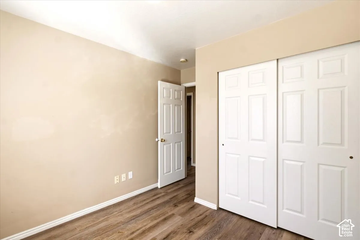 Room featuring wood-finish flooring, six-panel interior doors, and a double-door reach-in closet