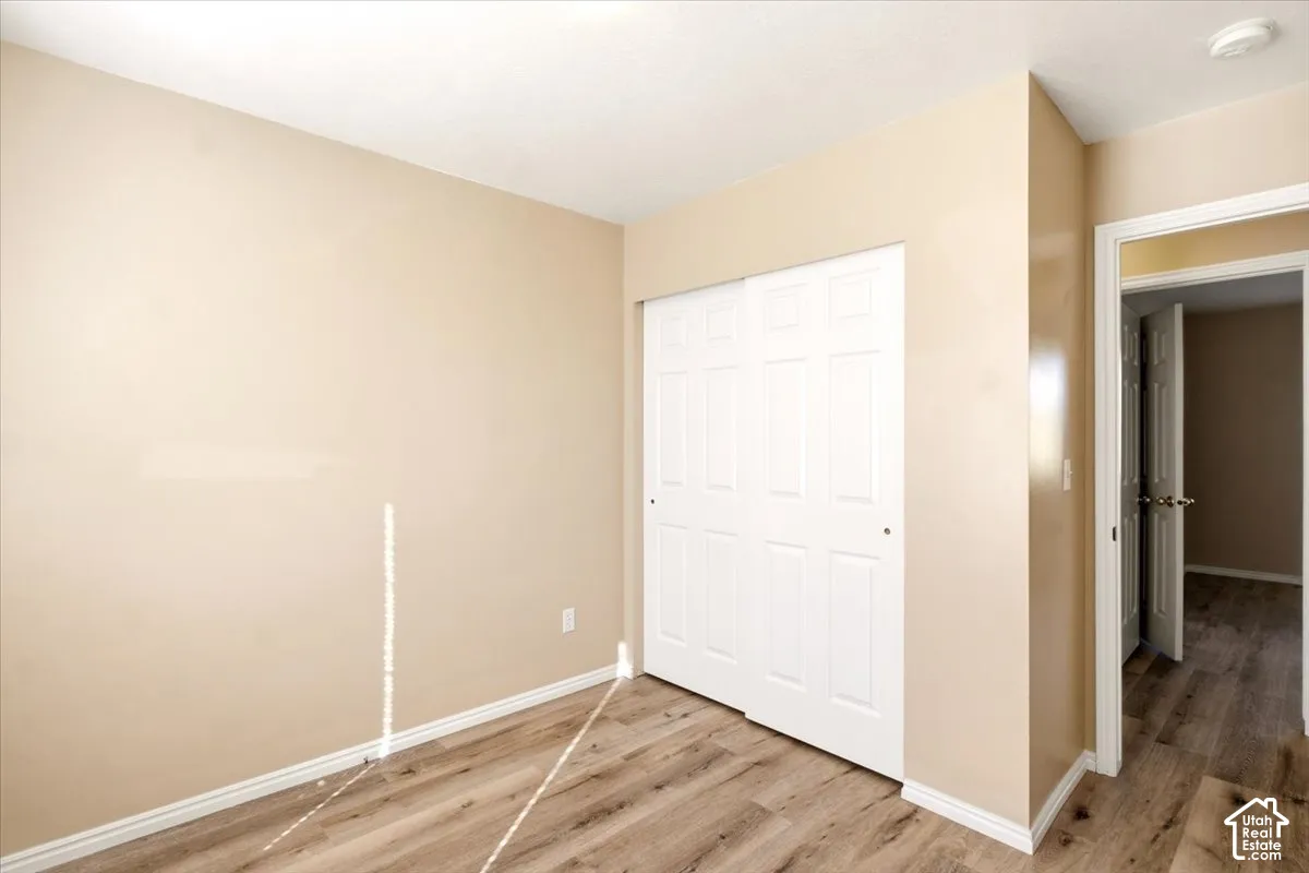 Neutral-toned wall finishes, wood-finish flooring, and white paneled sliding closet doors