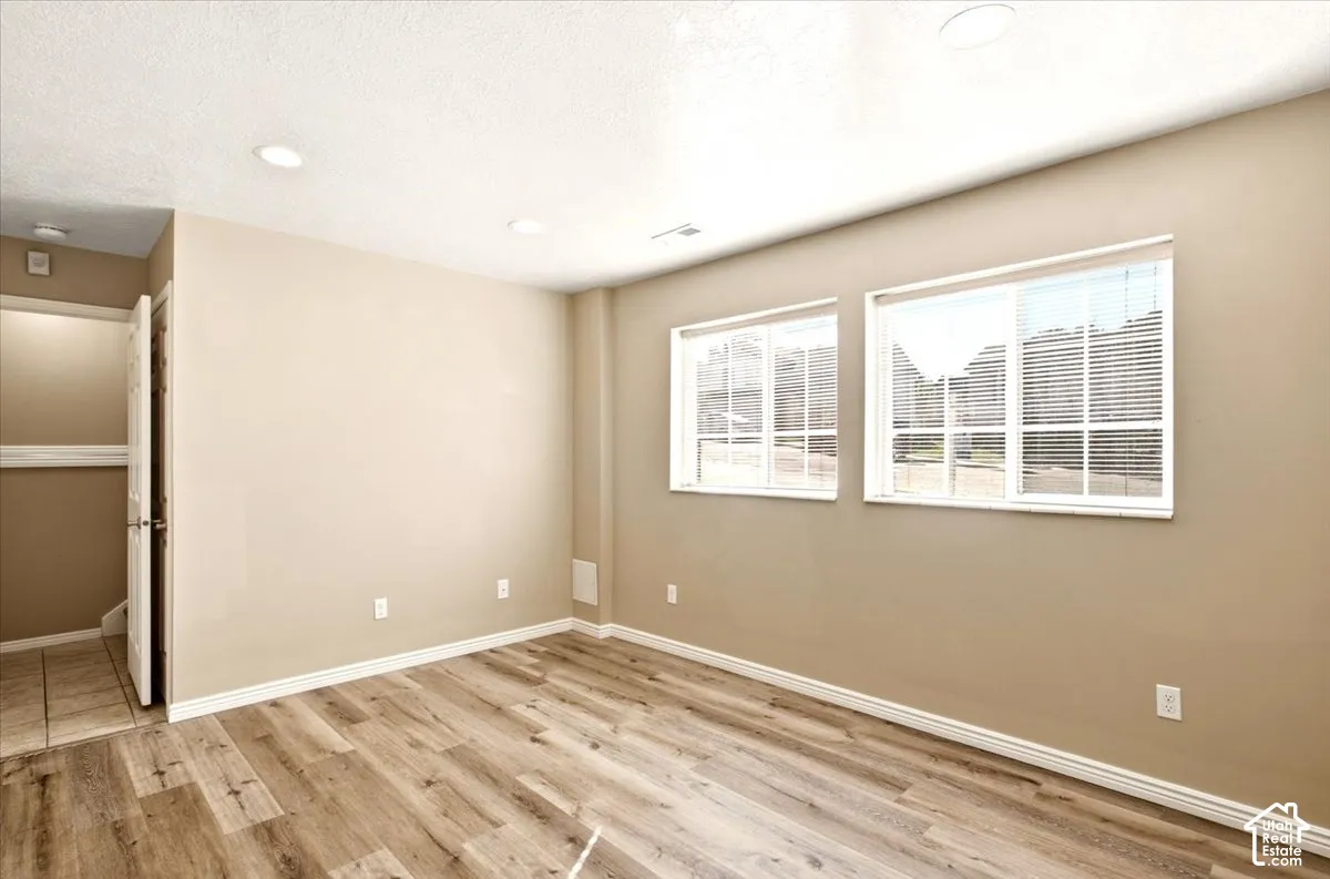 Neutral-toned interior room featuring wood-finish flooring, recessed lighting, and dual windows