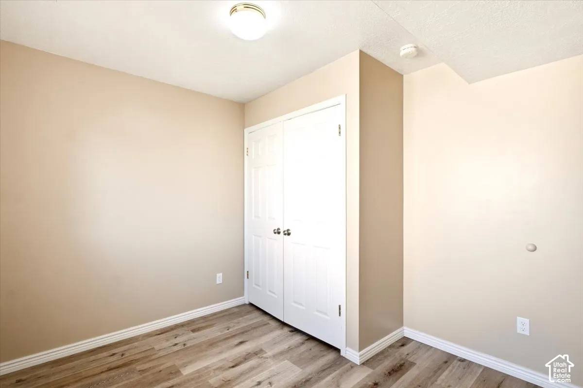 Neutral-toned interior featuring wood-finish flooring, a double-door closet with six-panel doors, and a flush-mount ceiling light fixture