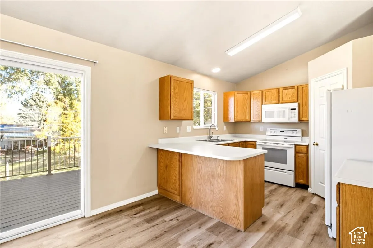 Kitchen featuring wood-finish flooring, wood cabinetry, a peninsula, and a sliding glass door providing external access