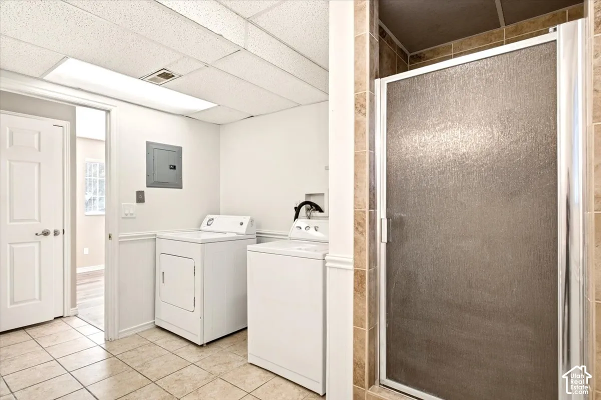Utility space featuring tile flooring, a walk-in shower with tile surround, laundry hookups, and a panel door