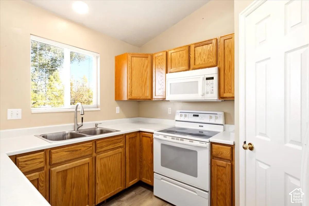 Kitchen featuring wood cabinetry, white countertops, double basin stainless steel sink with high-arc faucet, built-in microwave, and electric range