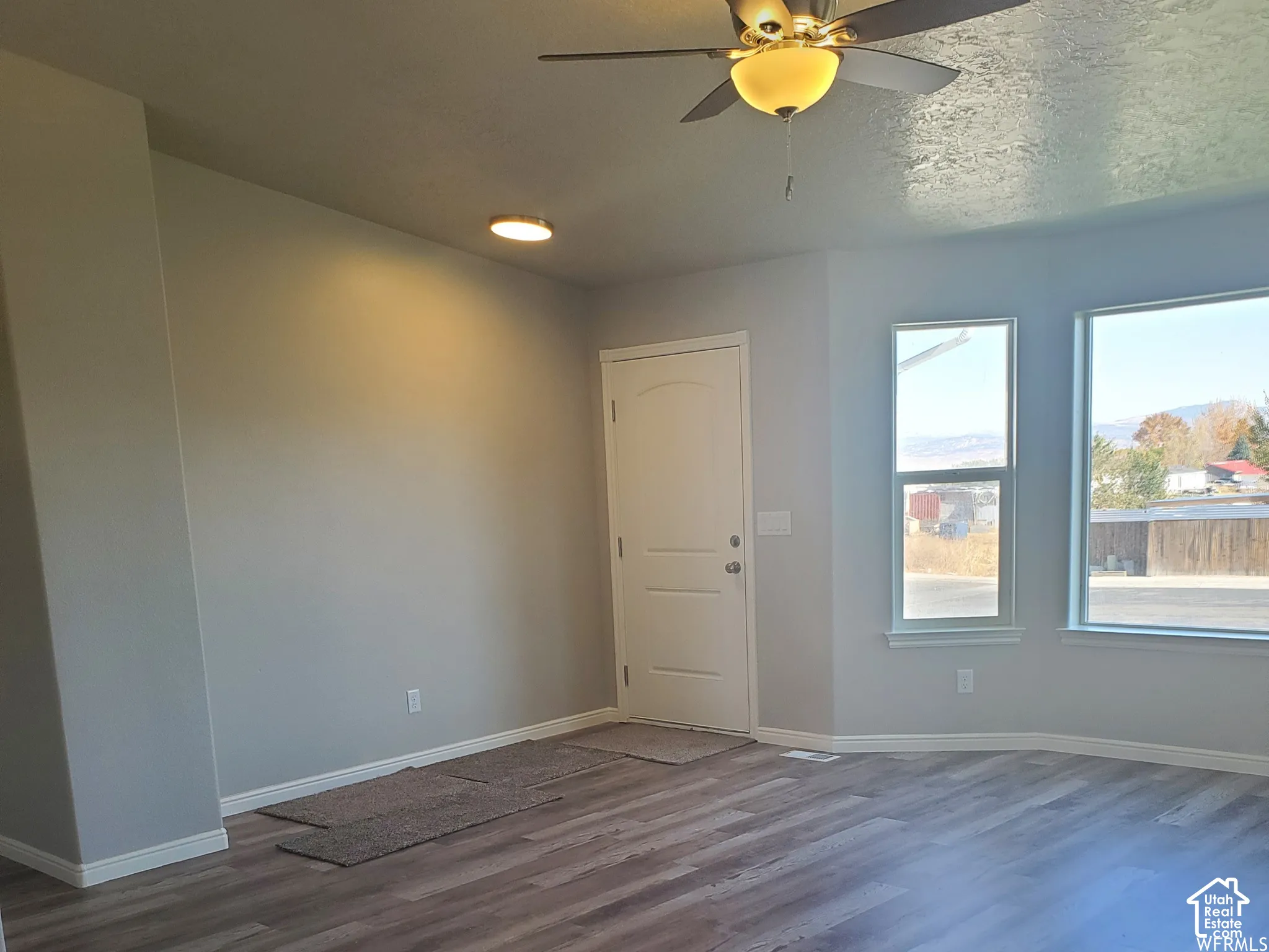 Wood-finish flooring, multi-pane windows, ceiling fan with integrated lighting, and a paneled entry door