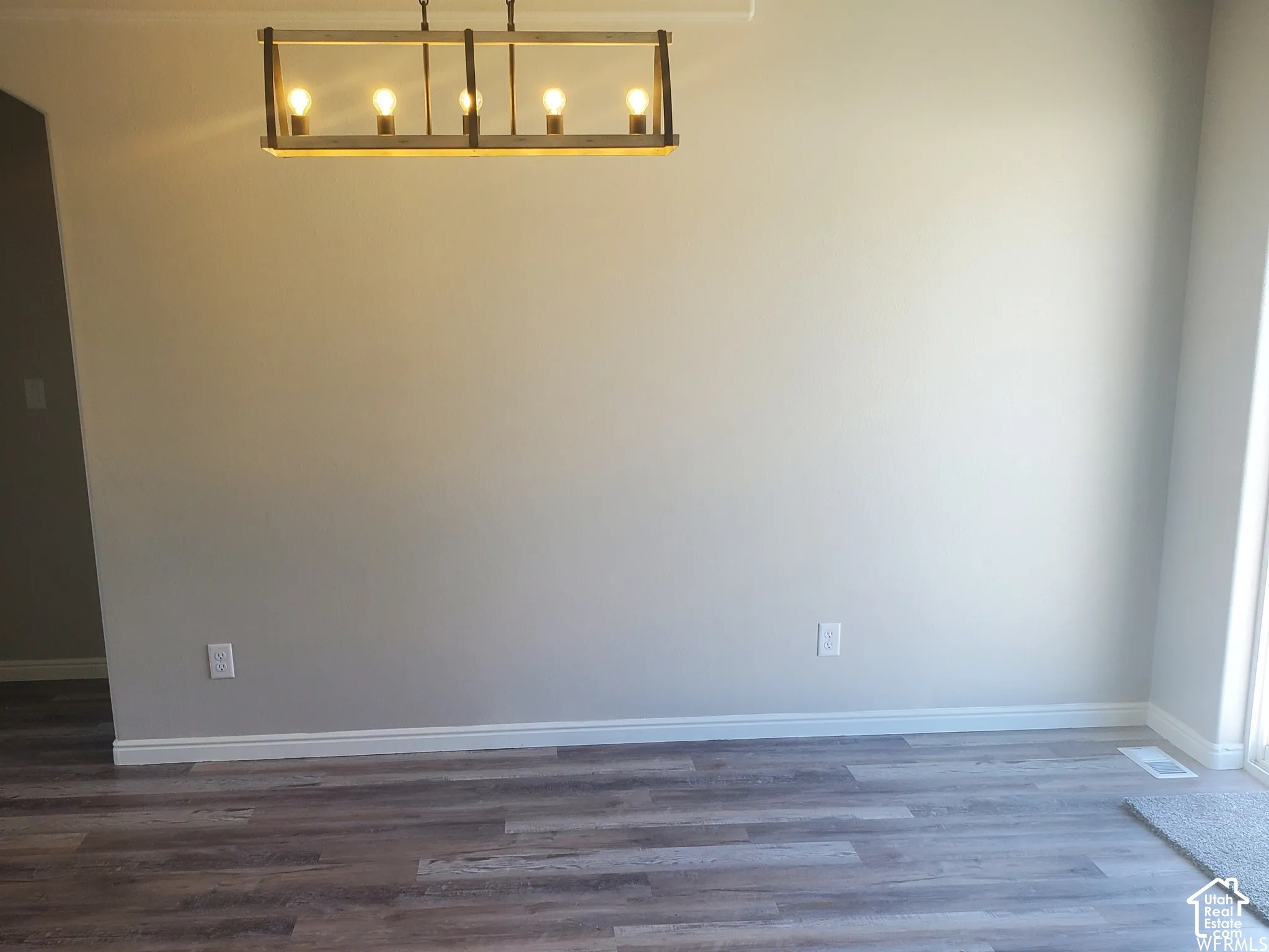 Rectangular, multi-bulb pendant light fixture with a geometric wood-finish frame and wood-finish flooring