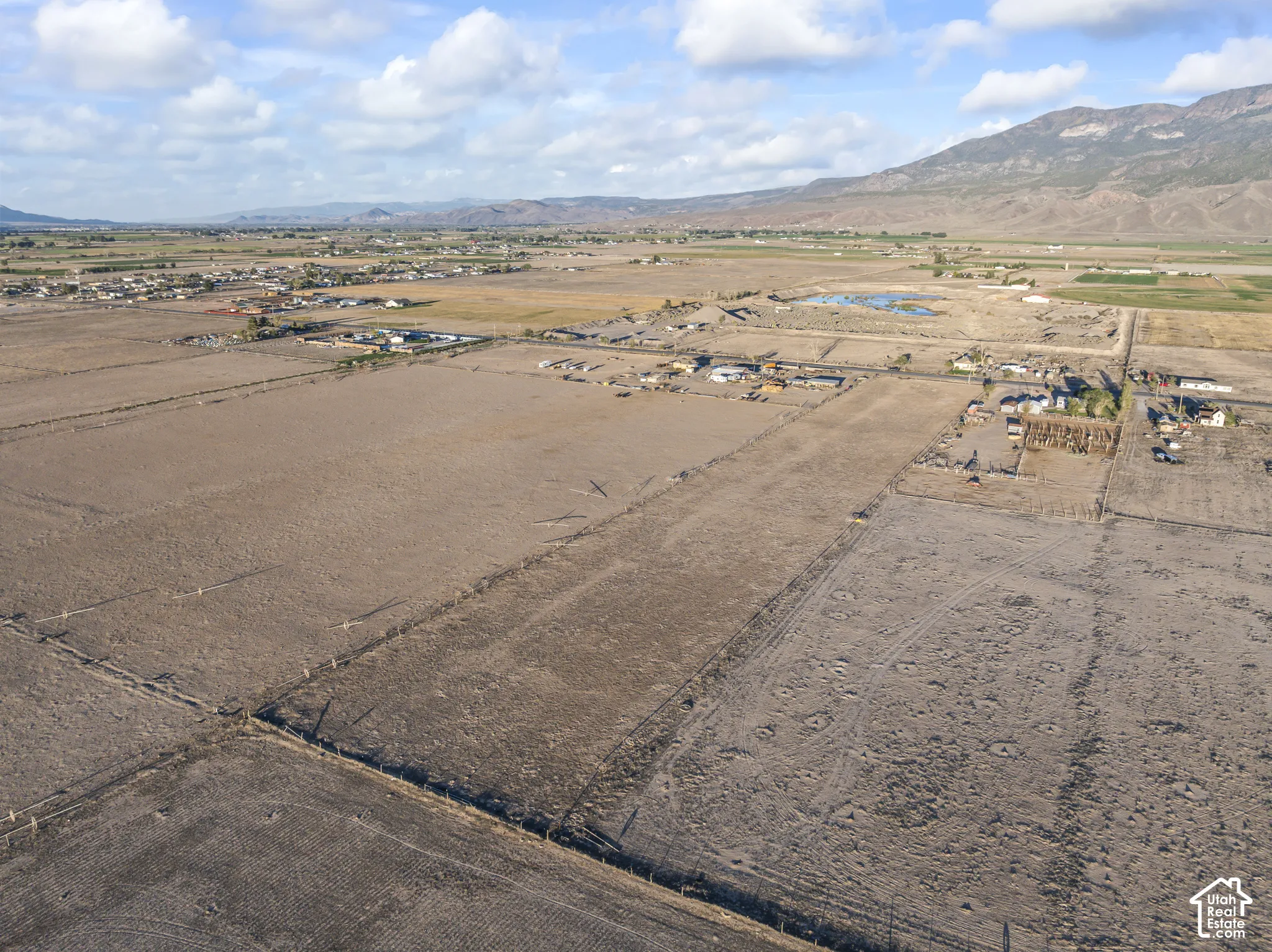 Expansive acreage featuring flat, open terrain, perimeter fencing, and prominent mountain backdrops