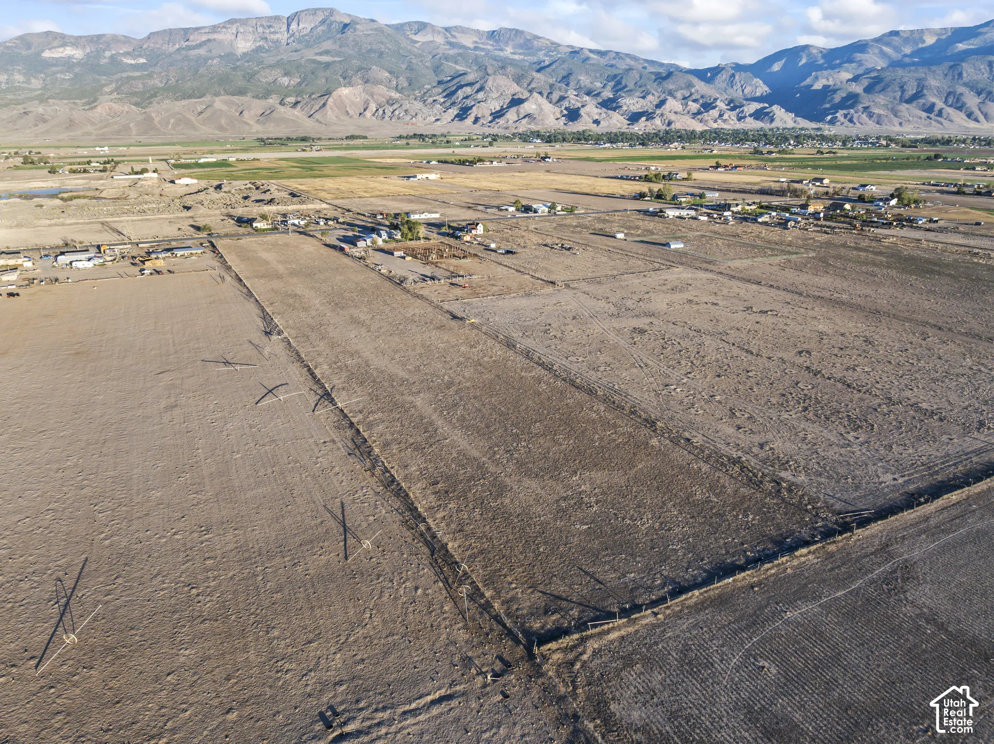 Expansive acreage featuring cleared land, wire perimeter fencing, and prominent mountain backdrops