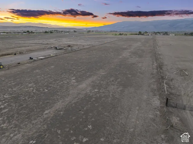 Expansive acreage featuring wire fencing, a metal gate, level topography, and mountain silhouettes against the horizon